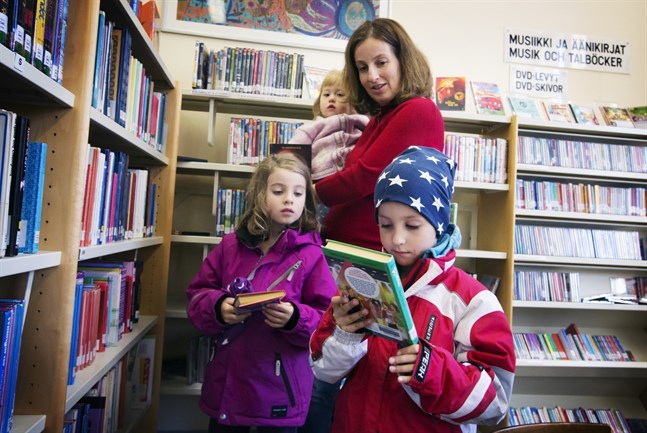 Maria Ehrnström-Fuentes hoppas att barnen Ester, Amanda och Gabriel Fuentes ska kunna låna böcker i Brändö bibliotek i många år framöver.