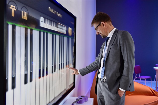 Jari Petäjä, direktör för barn och ungdomsenheten vid Helsingfors universitet, testar det digitala pianot i ungdomsrummet.