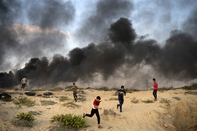 Unga palestinier springer från en protest i närheten av gränsen tidigare i veckan för att undvika tårgas. Vissa av demonstranterna har bränt bildäck vid gränsen för att undvika upptäckt. Arkivbild.