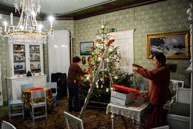 Julfirandet kan i år delvis tvingas anpassa sig till coronapandemin, särskilt på de håll där man är van att fira i stora sällskap. Här klär Inger Björkqvist och Eva Eveli julgranen på Kaskö hembygdsmuseum.