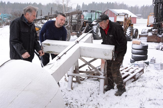 Per-Erik, Daniel och Lars-Åke Hannus tog ner det gamla korset från klockstapeln i Sideby och sedan dess har det förvarats på Näveråsen i Närpes. Nu ska korset förstöras. Bilden från december 2018.