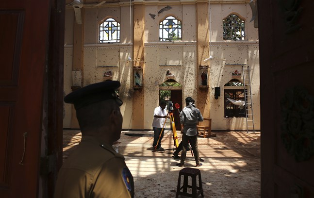 En polis står vakt när överlevare arbetar i kyrkan S:t Sebastian norr om huvudstaden Colombo.