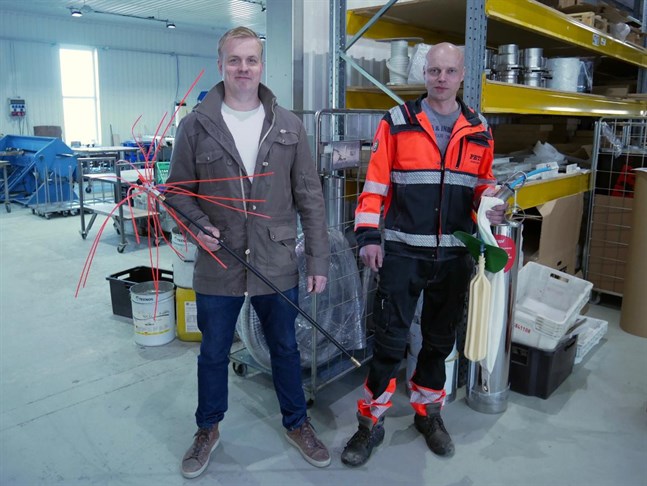 Kristian Lindfors till vänster håller i en skorstensputsare som används innan man kan renovera den. Toni Hakala till höger håller i en ballong som används vid gjutning av skorstenar.