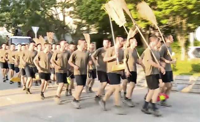 En bild från en videoupptagning visar kinesiska soldater med kvastar som anländer för att städa gator i Hongkong på lördagen.
