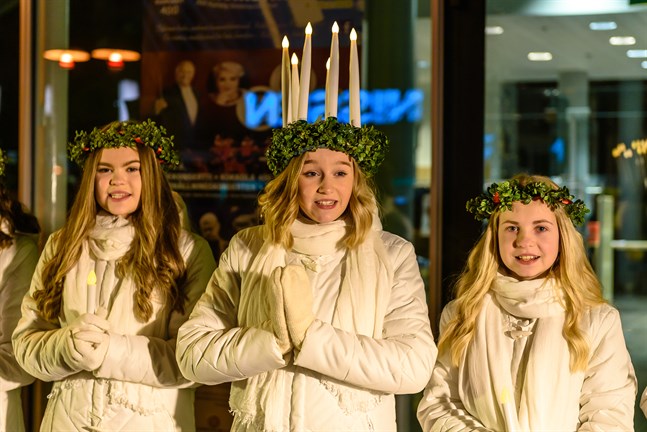 Lucia Marie Brunell med tärnorna Emma Vikman och Alma Långbacka sjunger utanför biblioteket under luciakvällen.