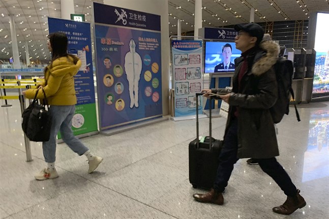 Resenärer passerar en hälsokontroll vid den internationella flygplatsen i Peking. Bilden togs den 13 januari.
