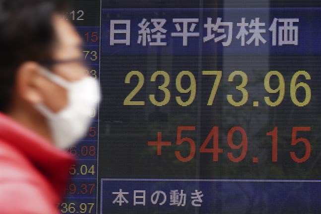 En man går förbi en skärm som visar Japans Nikkei 225-index.
