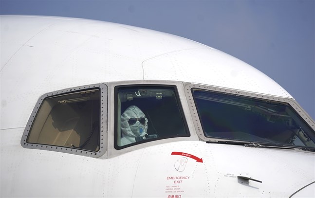 En pilot i skyddsutrustning i ett flygplan på flygplatsen i Wuhan.
