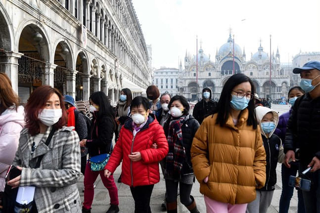 Turister i Venedig bär munskydd då de besöker Piazza San Marco. Över 1 000 personer har smittats av coronaviruset i Italien.