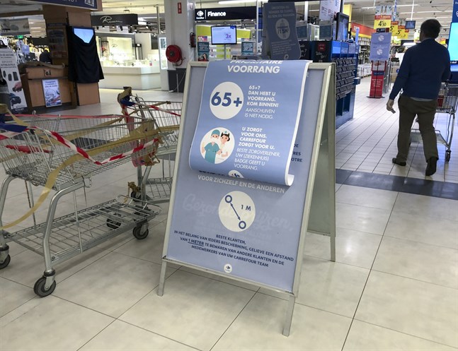 Skyltar i en belgisk matvarubutik manar till minst en meters avstånd mellan kunderna - och ger pensionärer och vårdanställda rätt att gå före i kön.
