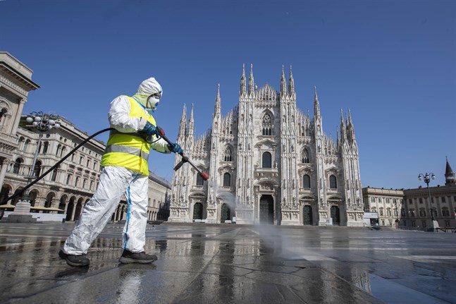 En man sprejar desinfektionsmedel på ett ödsligt Piazza del Duomo i Milano.