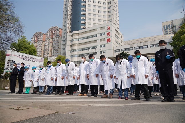 Sjukvårdspersonal i Wuhan under lördagens minnesstund.