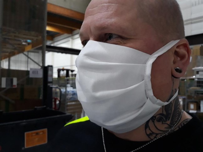 Tom Helin testar en ansiktsmask av tyg som vårdarna inom öppenvården ska använda. De ska tvättas i 90 grader efter några timmars användning.