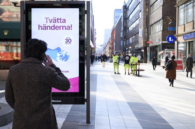 Informationsskylt på Drottninggatan i Stockholm som uppmanar folk att tvätta händerna.
