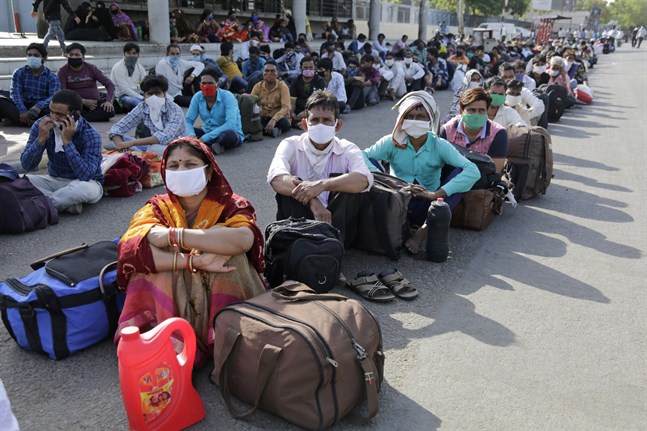 Migrantarbetare från andra delstater väntade på söndagen på en järnvägsstation i Ahmedabad i Indien. Tiotusentals migrantarbetare har mist arbetet på grund av nedstängningen i landet.