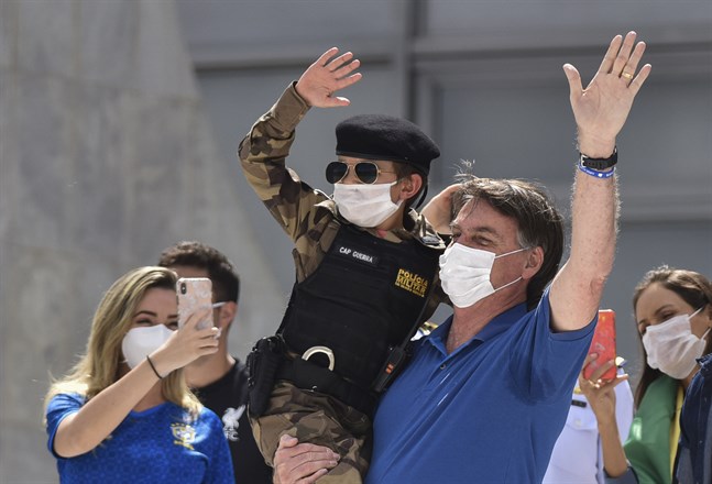 Brasiliens president Jair Bolsonaro med ett barn klädd i militärpolisuniform under en demonstration i Brasilia i söndags till stöd för presidentens krav på att avveckla coronarestriktioner och öppna upp ekonomin.