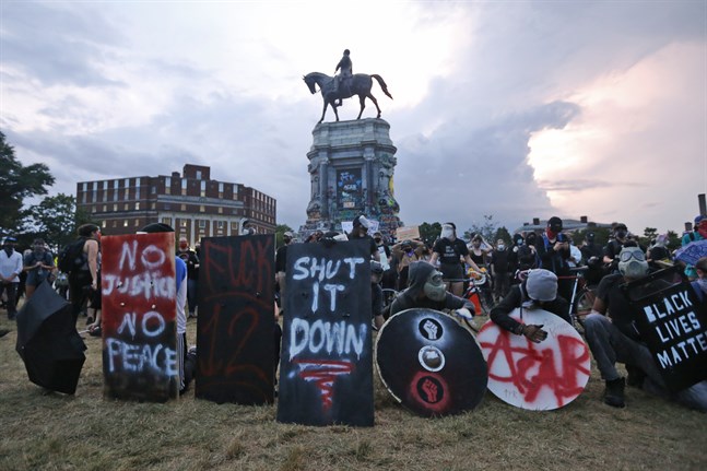 Demonstranter med sköldar omringar statyn på Robert E Lee i Richmond, Virginia. Staten har beslutat att hålla området runt statyn stängt mellan solnedgång och soluppgång.