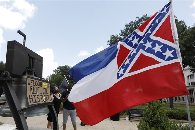 Mississippis flagga vajar utanför delstatens Capitolium i Jackson. Bakom den syns demonstranter som stödjer att flaggan ändras.