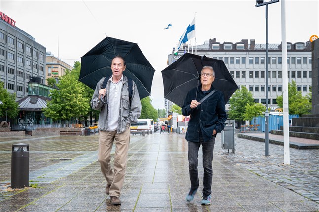 Jukka Kankaanpää, till vänster, och Gunnar Bäckman visar fotografier på en utställning utomhus i Vasa centrum.