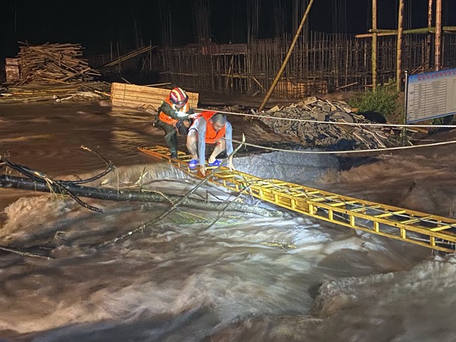 En räddningsarbetare hjälper en man att korsa ett översvämmat område i den kinesiska provinsen Jiangxi.