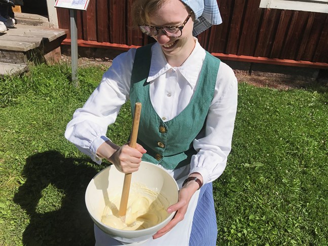 Dagen till ära är guiderna på Stundars klädda i gammaldags kläder. Här visar Annika Mäenpää hur man kärnar smör.