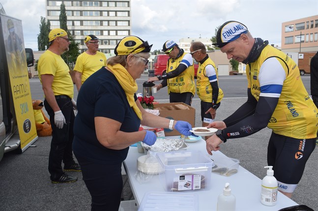 Ett sex personer stort serviceteam delar ut mat till cyklisterna med jämna mellanrum. Här Eivor Huldén och lagkapten Jari Lemberg.