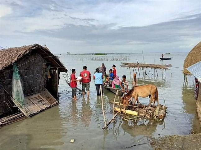 Volontärer från Röda Korset levererar vatten och andra förnödenheter till en familj i Kurigram. En fjärdedel av Bangladesh och en tredjedel av landets distrikt ligger under vatten.