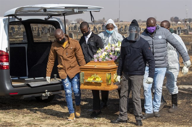 Familjemedlemmar och begravningsarbetare begraver en avliden i covid-19, i Thokoza, öster om Johannesburg, den 23 juli.