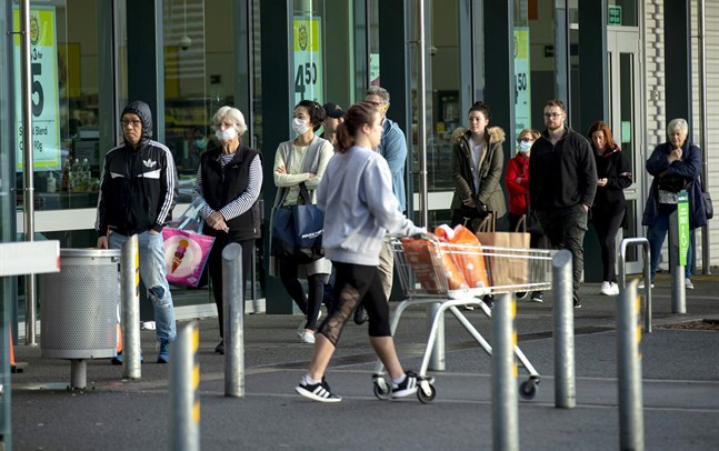 Människor köar utanför en livsmedelsbutik i Auckland.