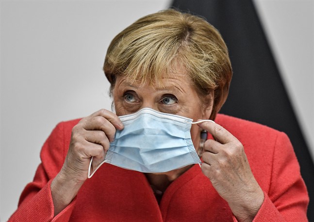 Angela Merkel tar på sig ett munskydd.