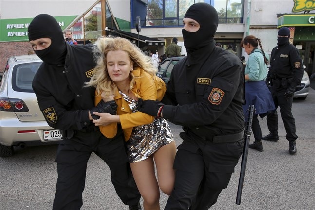 Belarusisk kravallpolis griper en demonstrant under lördagens demonstration i huvudstaden Minsk.