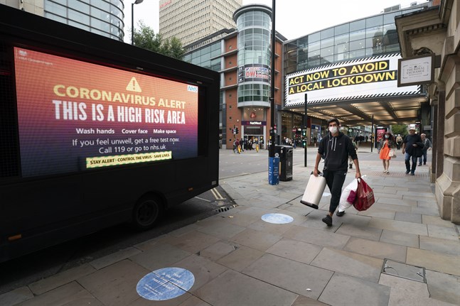 Varningsskyltar bland handlande människor i centrala Manchester i norra England i tisdags.