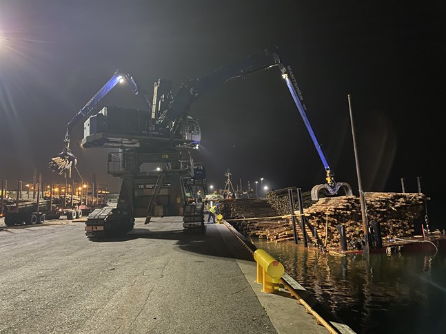 Två lyftkranar jobbar för fulla muggar på Alholmen med att tömma massveden från den olycksdrabbade pråmen som håller på att sjunka under vattenytan.
