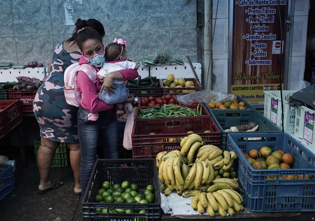 En kvinna med en bebis köper frukt i Rio de Janeiro.