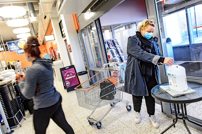 Sara Lindvall och Kajsa Mattbäck spritar omsorgsfullt händerna på väg in i affären.