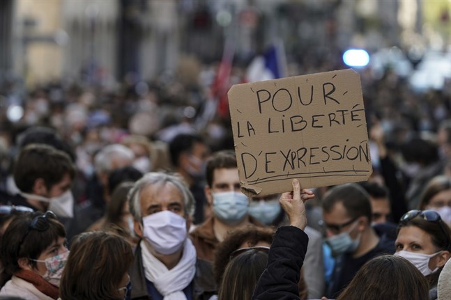 En man håller upp ett plakat med texten "För yttrandefrihet" vid en demonstration till stöd för den mördade läraren Samuel Paty, i Lyon.