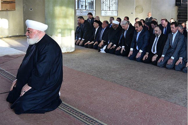 Adnan al-Afiyuni (till vänster), mufti för Damaskus-regionen, har dödats av en bilbomb. I bakgrunden syns också Syriens president Bashar al-Assad. Bild från 2016.