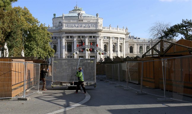 Arbetare bygger ett staket runt julmarknaden framför Burgtheater i Wien, vars öppning har skjutits upp på obestämd framtid.