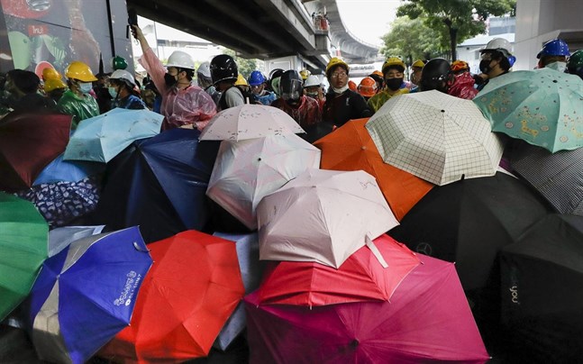 Demonstranter tar skydd under paraplyer vid en protest i Bangkok den 18 oktober.