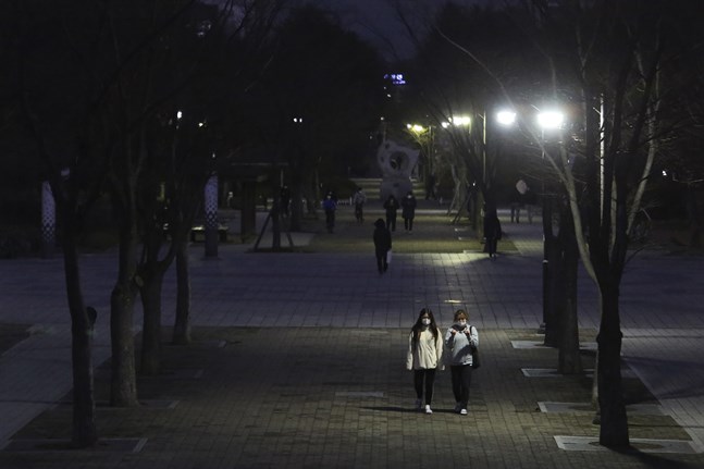 Två personer med munskydd på promenad längs en gata i Goyang, nordväst om Seoul, under söndagen.