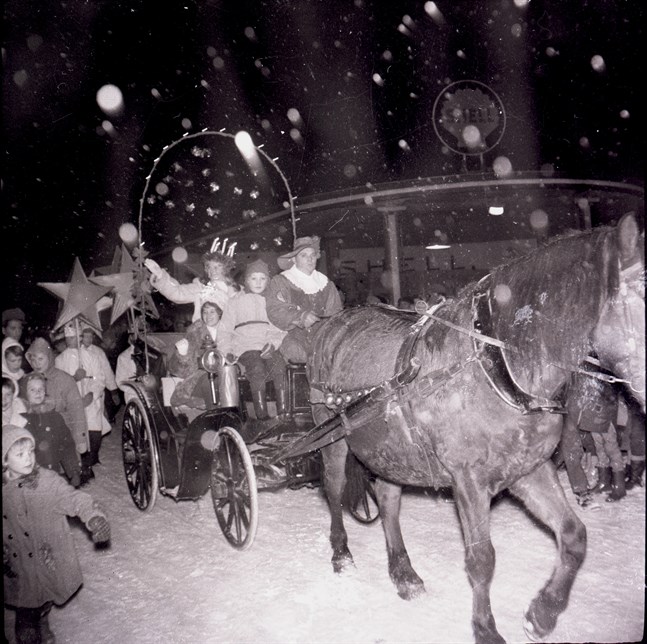Lucian 1960 Vivan Hassel åker i snöväder i vagnen längs Styrmansgatan förbi Shellstationen, som idag är en pub med uteterass.
