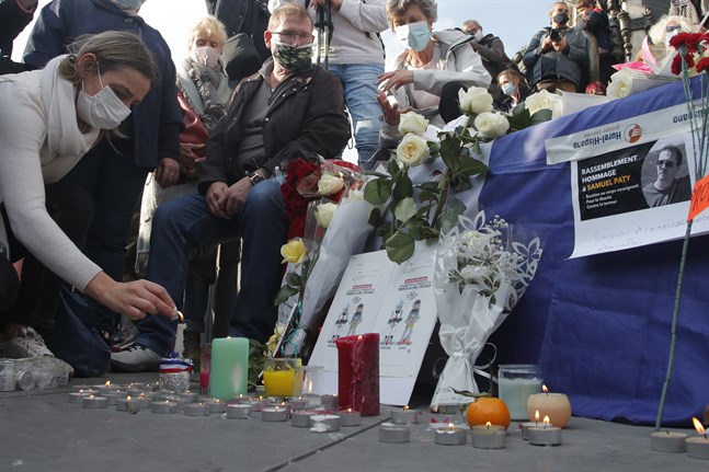 En kvinna tänder ett ljus under en demonstration i Paris efter mordet på Samuel Paty. Arkivbild.