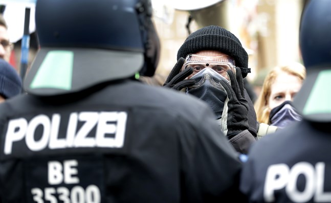 Myndigheternas restriktioner väcker ilskna reaktioner i Tyskland. Här står en demonstrant framför poliser vid en demonstration i Berlin förra veckan. Arkivbild.