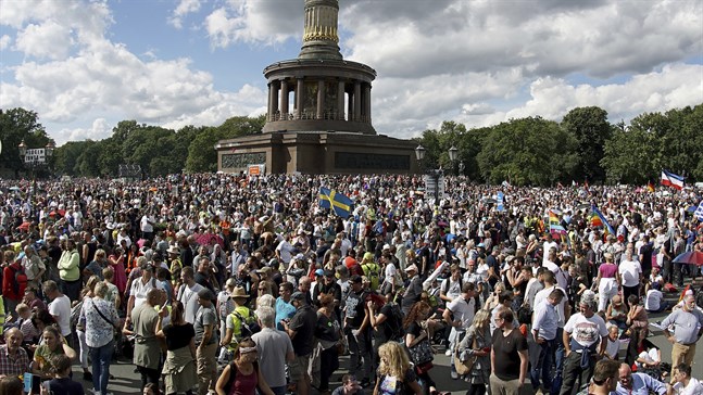 En svensk flagga vajar i vinden framför Siegessäule i Berlin, där tusentals personer samlades för en protest mot de tyska coronarestriktionerna i augusti i år.