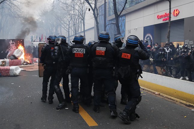 Kravallpolis närmar sig en brinnande barrikand under lördagens våldsamma protester i Paris.