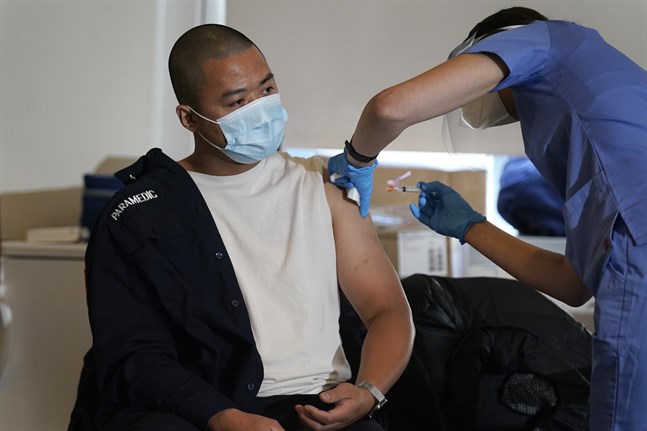 En ambulanssjukvårdare som arbetar för brandkåren i New York City får sin första spruta med covid-19-vaccin.