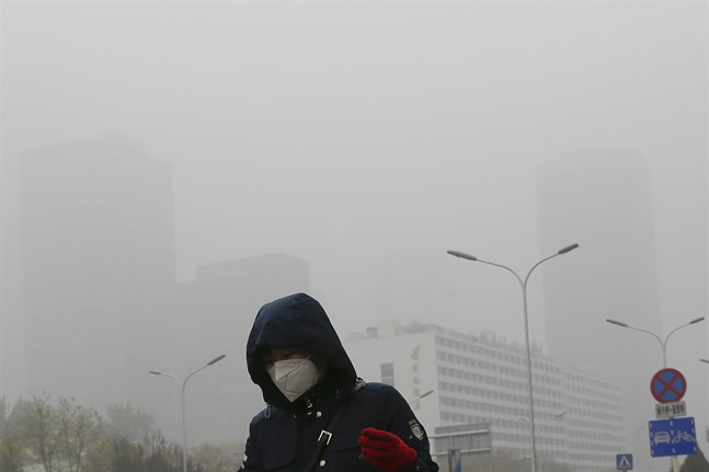 En kvinna skyddar sig mot föroreningar genom att använda munskydd i Peking. Bilden är från 2018.