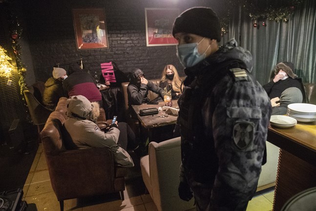 En polis inspekterar en bar i Moskva som brutit mot lokala restriktioner under julhelgen. Bilden är från den 26 december.