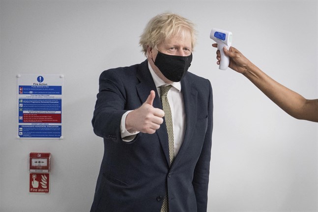 Storbritanniens premiärminister Boris Johnson tar tempen under ett besök på måndagen på ett sjukhus i norra London. På måndagskvällen gav han besked om strängare nedstängning från natten till tisdag.