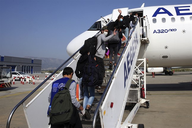 Ensamma barn som har suttit i överfulla migrantläger i Grekland kliver på ett plan i Aten som ska ta dem till Luxemburg, den 15 april 2020. Antalet internationella migranter minskade med 30 procent i fjol.